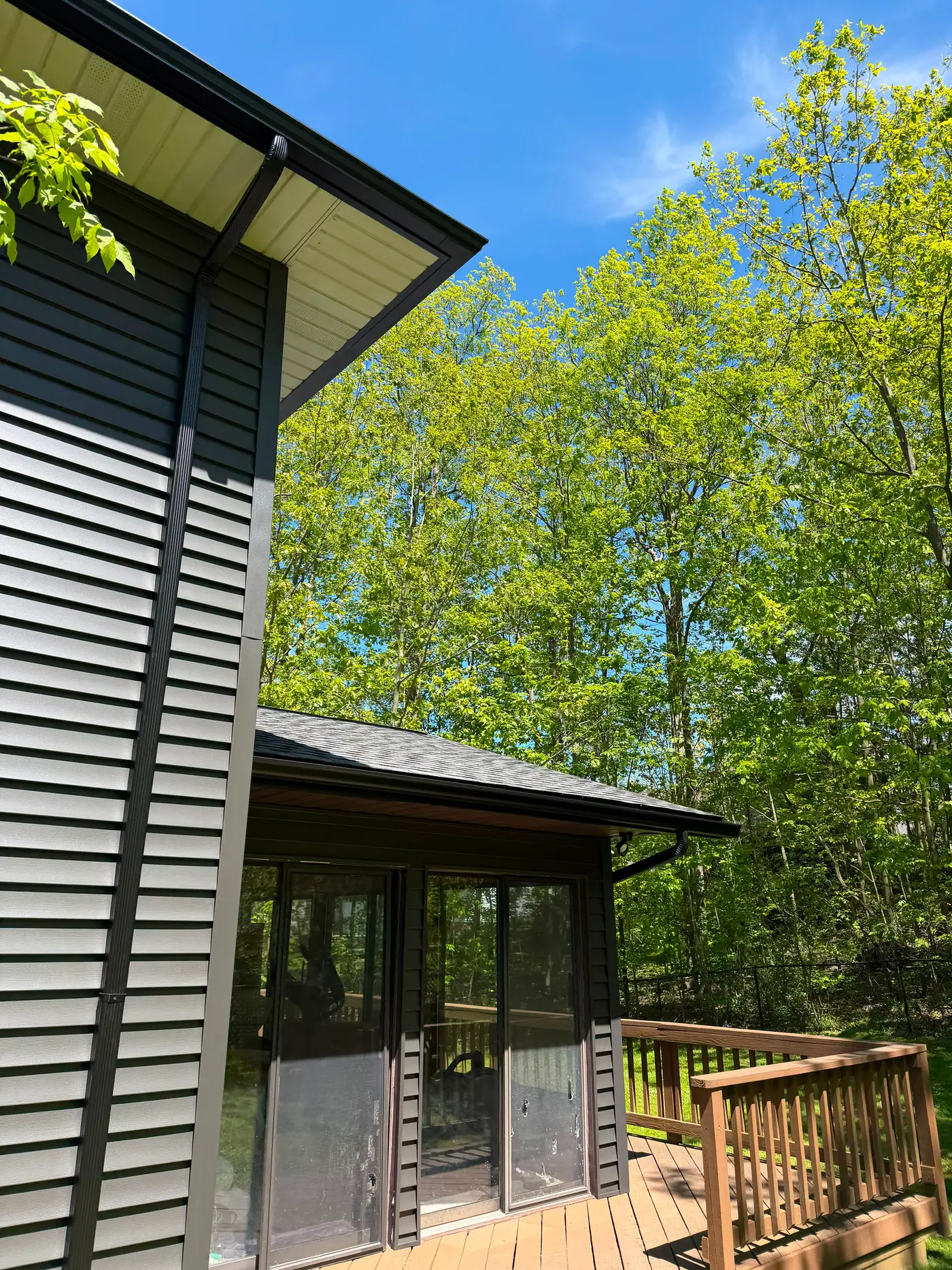 Gray siding with a black gutter and downspout beside a finished deck.